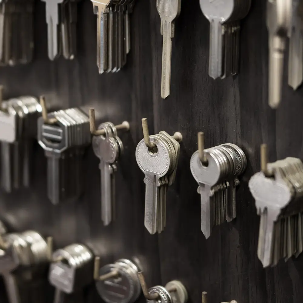 Close-up of several rows of silver keys hanging on metal pegs against a dark background, emphasizing organization and security tips with the neatly arranged, overlapping keys.